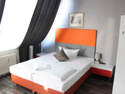 Doppelzimmer mit orangefarbenem Kopfteil